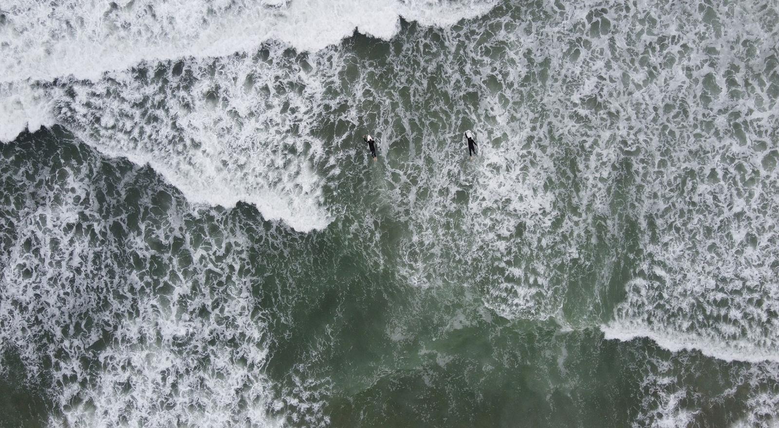 Aerial view of two surfers waiting in the whitewater